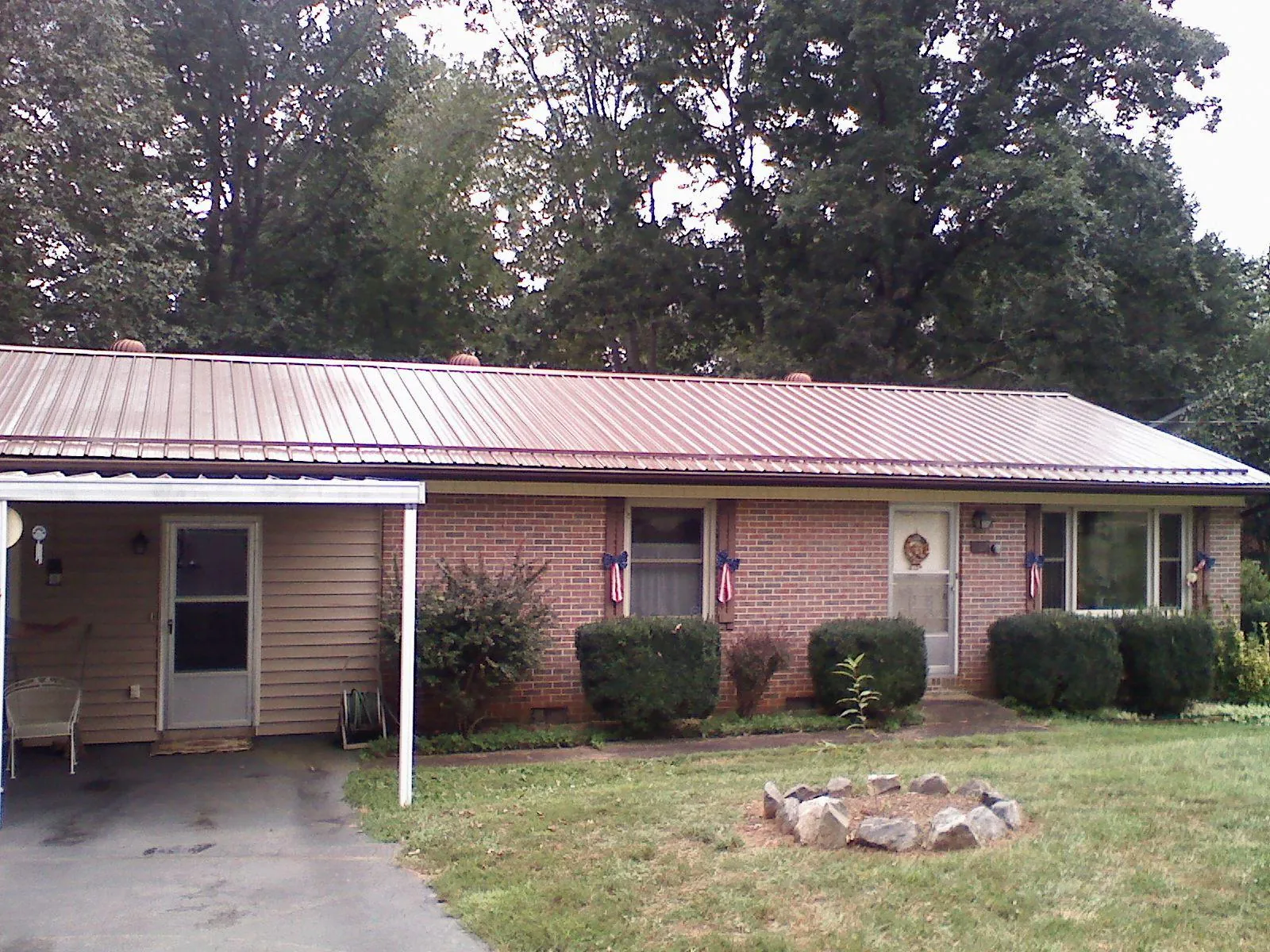 Bronze metal roof and carport on a brick ranch home — Roof Repair work by our crew in Groveland
